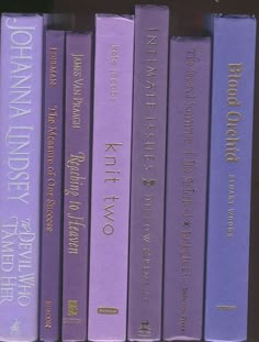 a row of purple books sitting on top of a shelf