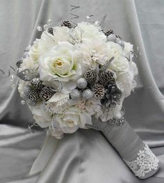 a bridal bouquet with white flowers and pine cones