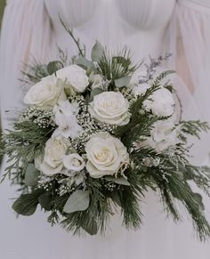 a bridal holding a bouquet of white flowers and greenery