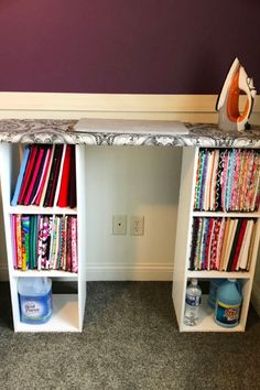 an ironing board sitting on top of a white desk next to a book shelf filled with books