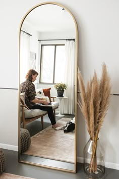 a woman sitting on a chair in front of a large mirror with her legs crossed