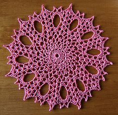 a crocheted doily on a wooden surface