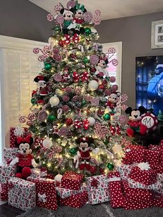 a christmas tree decorated with minnie mouses and candy canes is surrounded by presents