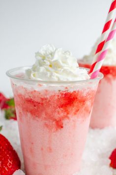 two strawberry milkshakes with whipped cream and strawberries on the side, sitting in snow