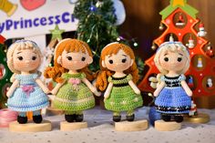 four little knitted dolls standing next to each other in front of a christmas tree