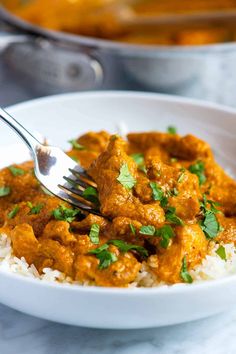 a white bowl filled with rice and meat covered in gravy, garnished with cilantro