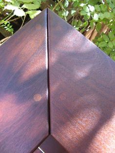 the corner of a wooden bench in front of some plants