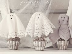 three little white ghost decorations sitting on top of a shelf