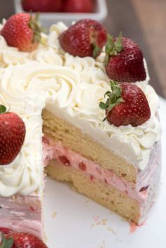 there is a cake with white frosting and strawberries on the top it has one slice cut out