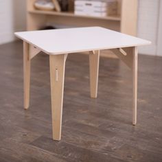 a small white table sitting on top of a hard wood floor next to a book shelf