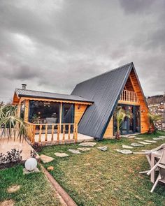 a small wooden cabin with a metal roof on top of a grassy field next to a picnic table and chairs