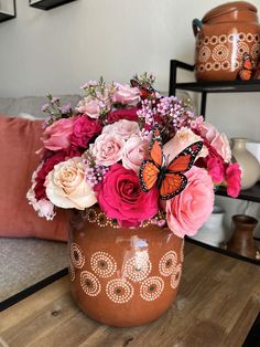 a vase filled with lots of pink flowers on top of a wooden table next to a couch