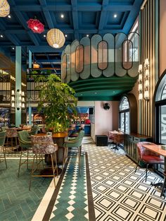 the interior of a restaurant with tables, chairs and potted plant on the floor