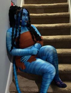 a woman in blue and orange costume sitting on stairs