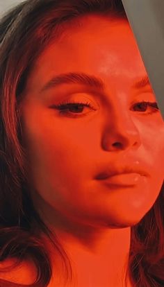 a woman is staring at the camera with an orange light on her face and hair