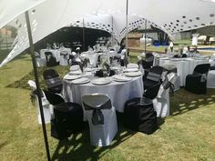 tables and chairs are set up under an umbrella for a wedding reception in the grass