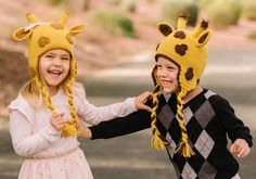 two children wearing knitted hats with giraffes on their heads and braids