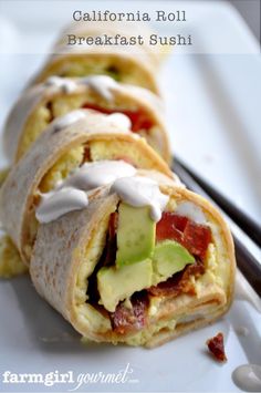 breakfast burritos with bacon, avocado and ranch dressing on a white plate