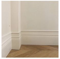 an empty room with white walls and wood flooring is pictured in this image from the corner