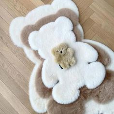 a teddy bear is laying on top of a fluffy rug in the middle of a wood floor