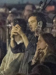 two people taking pictures with their cell phones in front of an audience at a concert