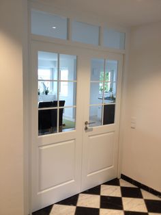 two white double doors with black and white checkered flooring in an empty room