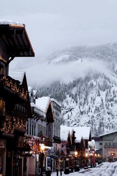 the town is decorated for christmas with lights and snow on the mountain in the background