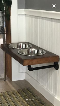 the dog bowl is mounted to the wall with two metal bowls on it's shelf