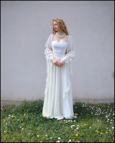 a woman in a white dress is standing on the grass with her hands behind her back