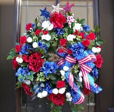 a wreath with red, white and blue flowers on the front door for memorial day