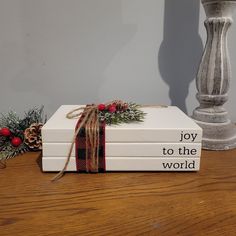 a stack of books sitting on top of a wooden table next to a candle holder