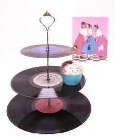 three records stacked on top of each other with a cupcake in front of them