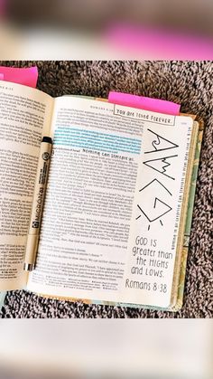 an open bible with pink markers on it