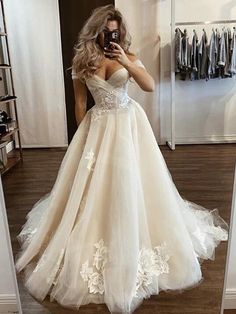 a woman in a wedding dress taking a selfie with her cell phone while looking into the mirror