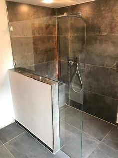 a bathroom with a glass shower door and tiled walls