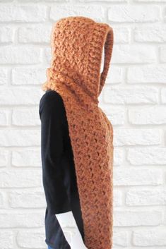 a crocheted hooded scarf is shown in front of a brick wall