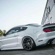 a white mustang parked in front of a building