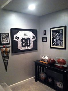 a football jersey hangs on the wall in a sports themed room with posters and memorabilia