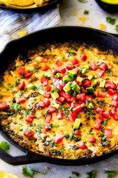 an omelet with tomatoes, avocado and cilantro in a cast iron skillet