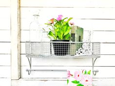 a metal shelf with flowers and bottles on it next to a white house window sill