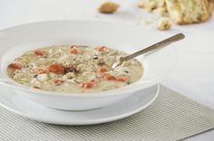 a white bowl filled with soup on top of a table next to cookies and bread