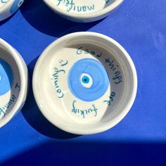 three white bowls with blue and green designs on the rims that have words written on them