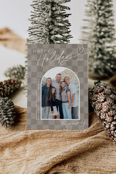 a christmas card with the words happy holidays on it and pine cones in front of it