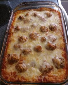 a casserole dish with meatballs and cheese in it sitting on the stove