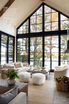 a living room filled with lots of white furniture and large windows overlooking the trees outside