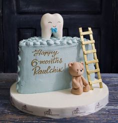 a cake with a toothbrush and teddy bear on it, sitting next to a ladder