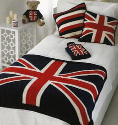 a bed with two pillows and a union jack blanket on it, next to a teddy bear