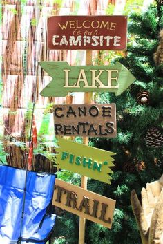 wooden signs pointing in different directions near a christmas tree with pine cones and other decorations