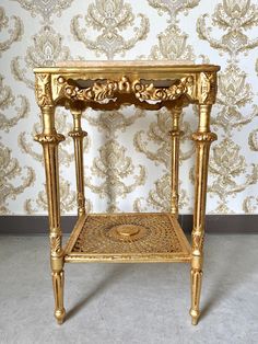 an ornate gold side table against a wallpapered background