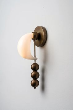 a wall mounted light on the side of a white wall with two balls hanging from it